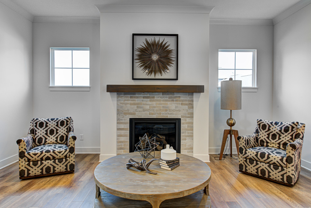 Cette image montre un salon craftsman de taille moyenne et ouvert avec un mur blanc, un sol en vinyl, une cheminée standard, un manteau de cheminée en carrelage et un sol marron.