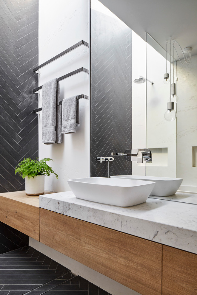 This is an example of a contemporary bathroom in Melbourne with flat-panel cabinets, light wood cabinets, gray tile, white walls, a vessel sink and grey floor.