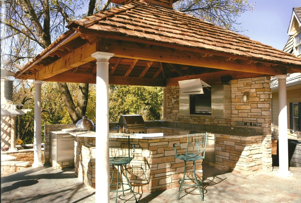Inspiration for a mid-sized mediterranean backyard patio in Wichita with an outdoor kitchen, natural stone pavers and a roof extension.