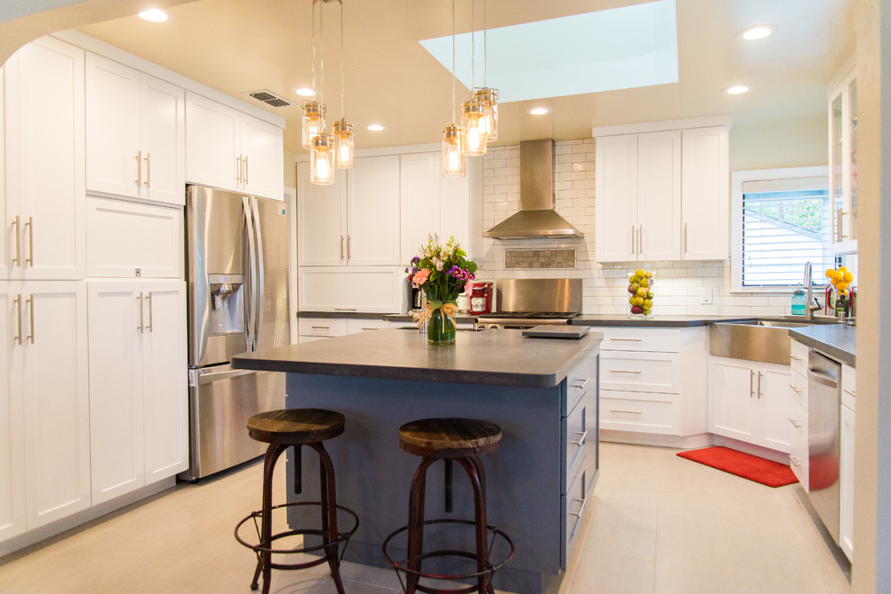 Inspiration for a transitional porcelain tile kitchen remodel in Sacramento with a farmhouse sink, shaker cabinets, white cabinets, white backsplash, subway tile backsplash, stainless steel appliances and an island