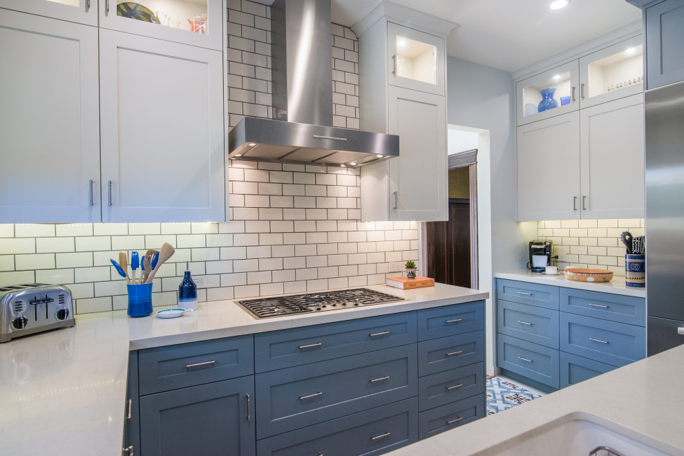 Mid-sized transitional u-shaped ceramic tile and multicolored floor enclosed kitchen photo with an undermount sink, shaker cabinets, blue cabinets, limestone countertops, white backsplash, subway tile backsplash, stainless steel appliances, a peninsula and white countertops