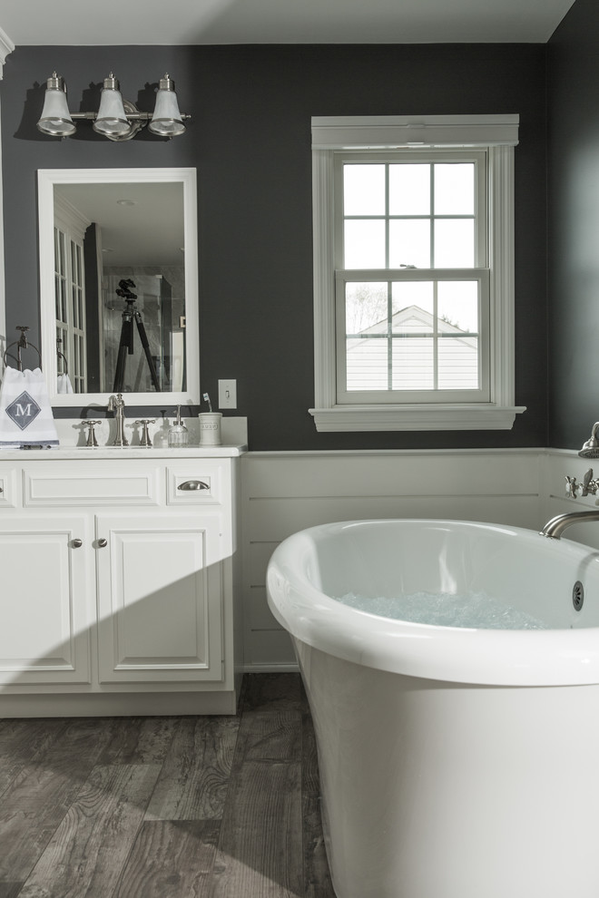 Inspiration for a mid-sized country master bathroom in Philadelphia with raised-panel cabinets, white cabinets, a freestanding tub, an open shower, a two-piece toilet, gray tile, porcelain tile, grey walls, porcelain floors, an undermount sink, engineered quartz benchtops, grey floor and a hinged shower door.