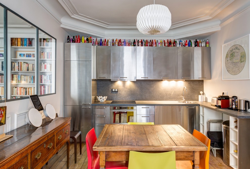 Mid-sized eclectic l-shaped eat-in kitchen in Paris with a single-bowl sink, stainless steel cabinets, grey splashback, stainless steel appliances, light hardwood floors and no island.