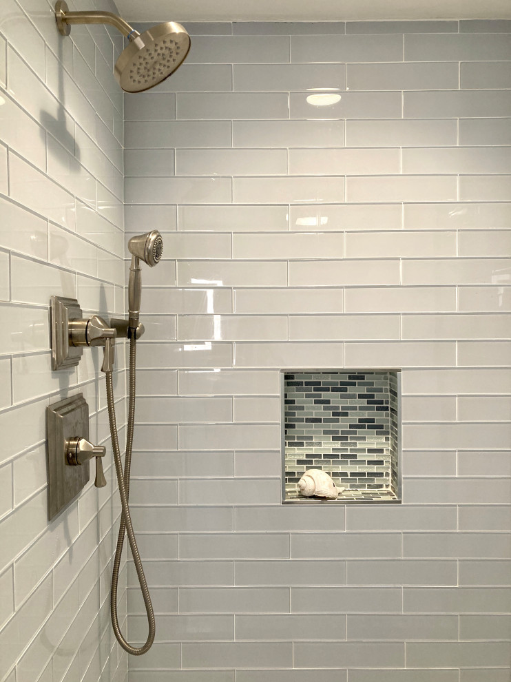 This is an example of a mid-sized beach style master bathroom in Boston with shaker cabinets, white cabinets, an alcove shower, blue tile, glass tile, blue walls, porcelain floors, an undermount sink, engineered quartz benchtops, blue floor, a hinged shower door, blue benchtops, a single vanity, a bidet and a freestanding vanity.