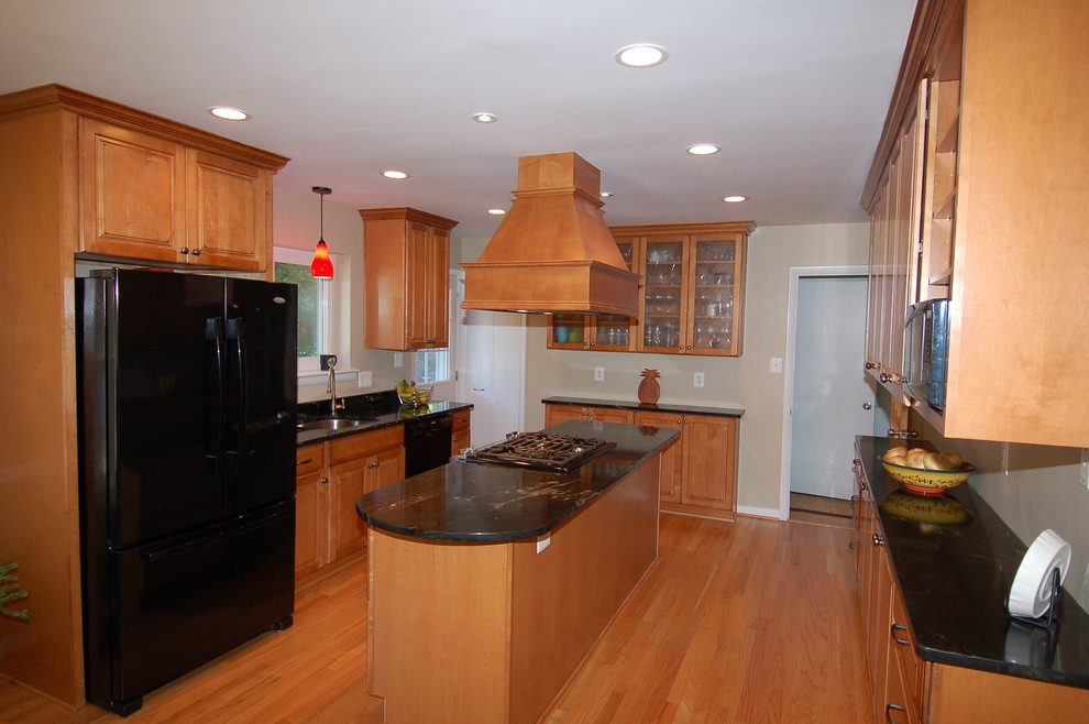 Mid-sized traditional u-shaped separate kitchen in DC Metro with an undermount sink, raised-panel cabinets, medium wood cabinets, quartzite benchtops, black appliances, medium hardwood floors, with island and brown floor.
