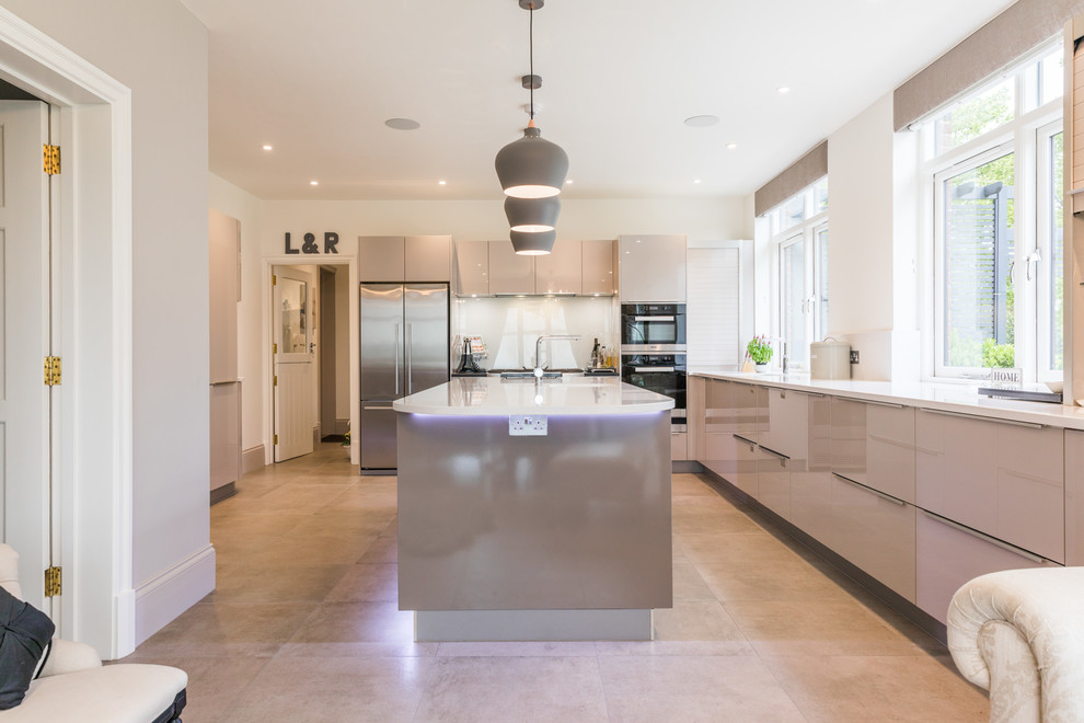 Photo of a large modern kitchen in London with glass-front cabinets, white splashback, glass sheet splashback, with island and white benchtop.