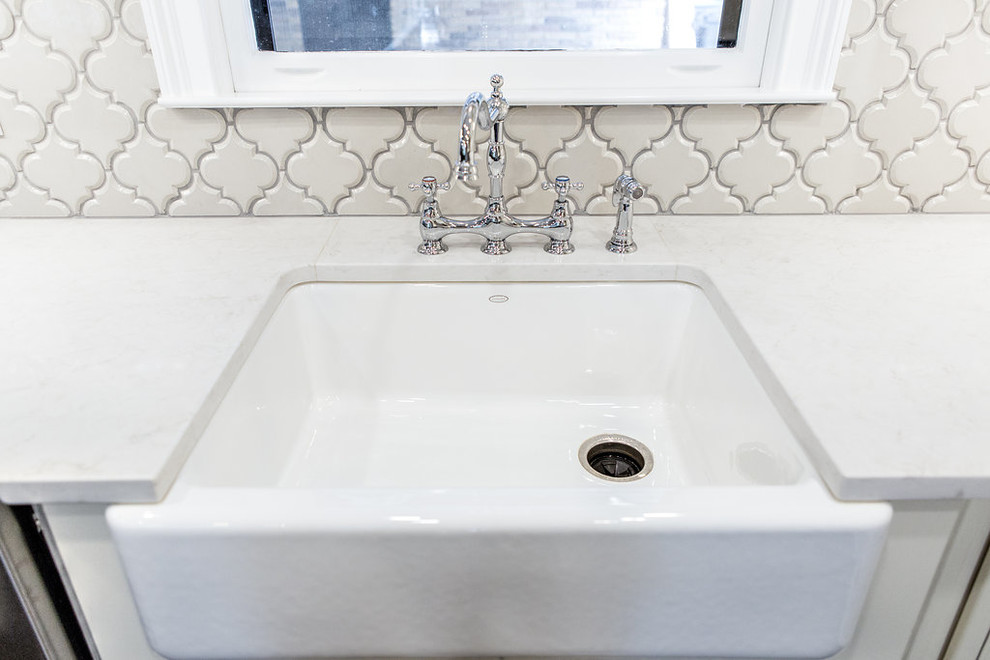 Large l-shaped medium tone wood floor bathroom photo in Birmingham with a farmhouse sink, raised-panel cabinets, white cabinets, granite countertops, white backsplash, ceramic backsplash, stainless steel appliances and an island