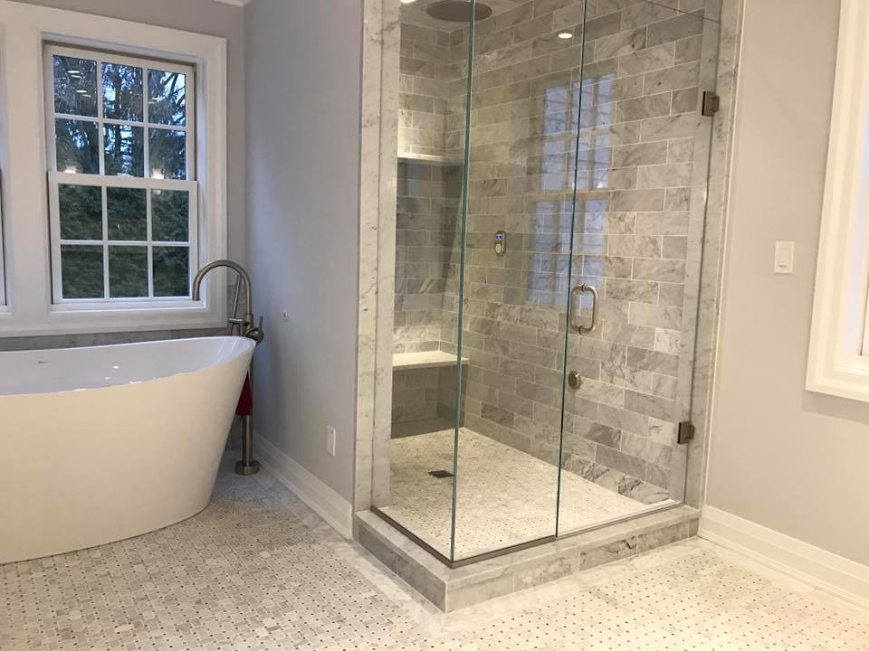 Photo of an expansive contemporary master bathroom in New York with shaker cabinets, white cabinets, a freestanding tub, an alcove shower, a two-piece toilet, gray tile, subway tile, grey walls, mosaic tile floors, an undermount sink and granite benchtops.