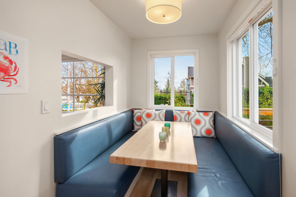 Inspiration for a mid-sized transitional u-shaped light wood floor enclosed kitchen remodel in Seattle with an undermount sink, shaker cabinets, white cabinets, quartz countertops, blue backsplash, glass tile backsplash, stainless steel appliances and white countertops