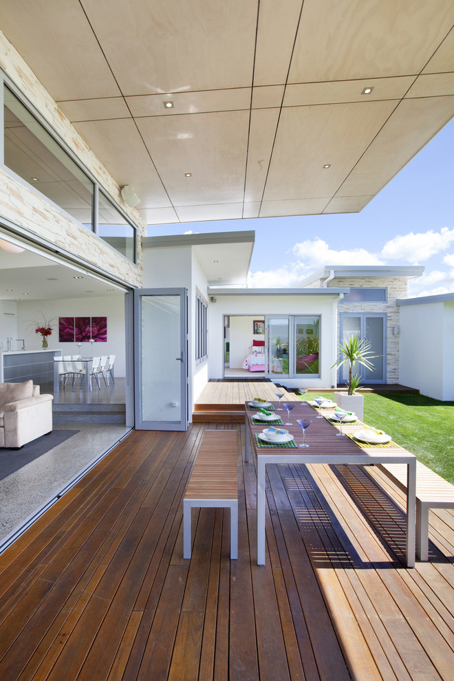 This is an example of a modern deck in Other with a roof extension.