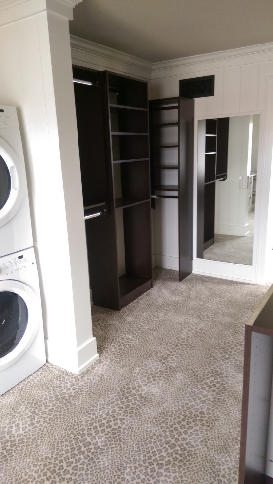 Photo of a mid-sized laundry room in Other with dark wood cabinets and carpet.