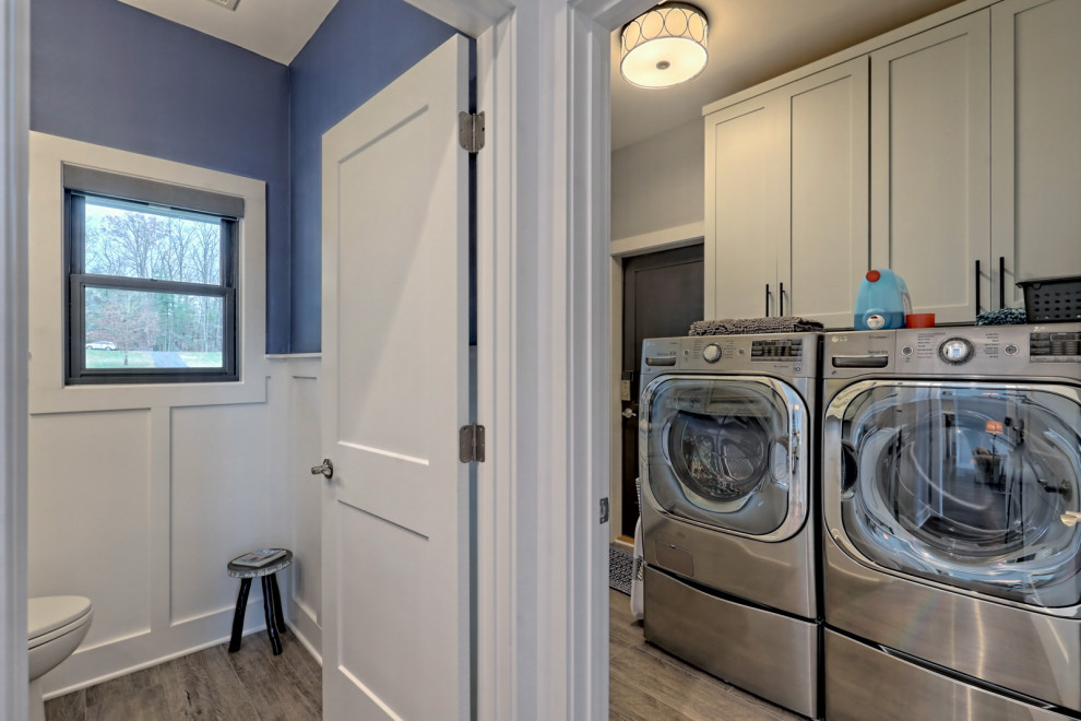 Mid-sized transitional single-wall dedicated laundry room in Atlanta with shaker cabinets, grey cabinets, grey walls, vinyl floors, a side-by-side washer and dryer and grey floor.