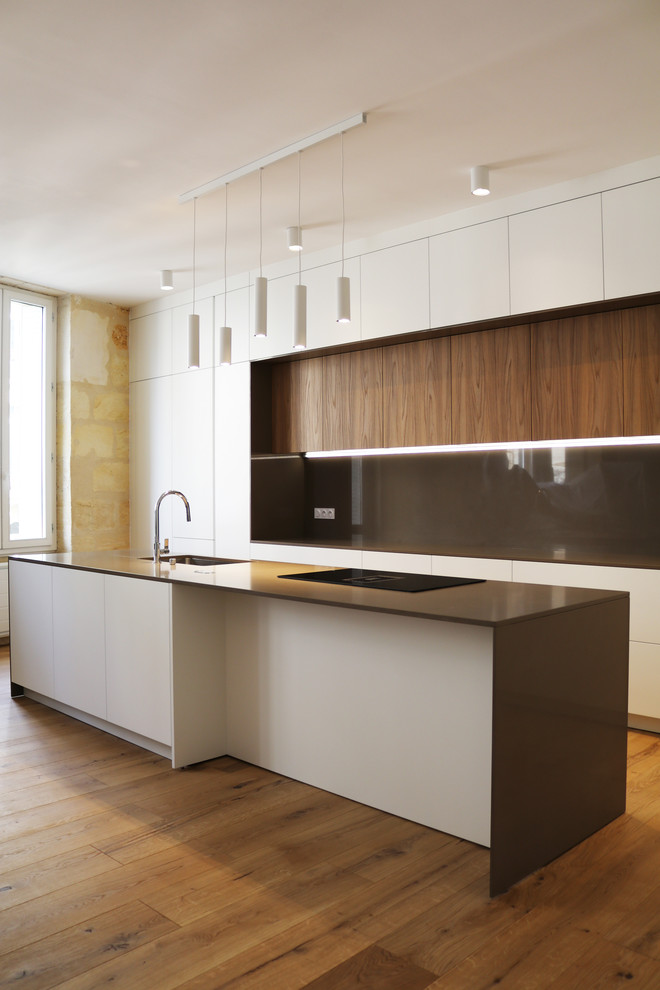 Design ideas for an expansive contemporary galley open plan kitchen in Bordeaux with an undermount sink, beaded inset cabinets, white cabinets, quartz benchtops, brown splashback, panelled appliances, light hardwood floors, with island, brown floor and brown benchtop.