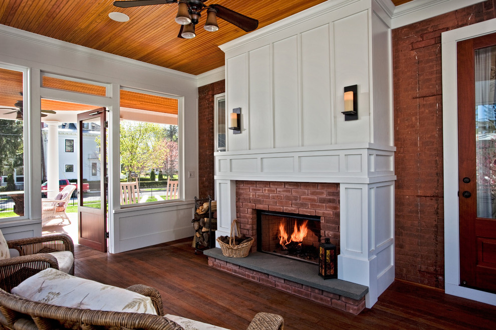 Mid-sized traditional sunroom in Boston with dark hardwood floors, a standard ceiling, a brick fireplace surround and a standard fireplace.