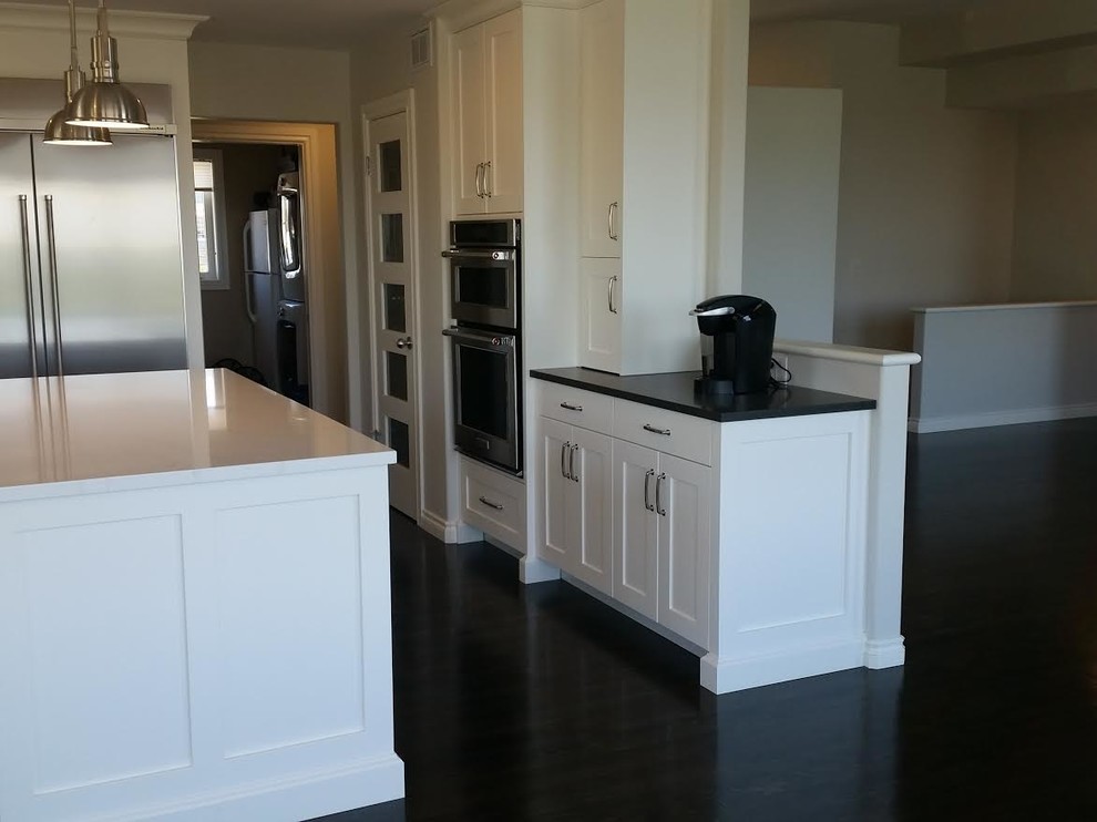 Kitchen - mid-sized transitional dark wood floor and brown floor kitchen idea with a farmhouse sink, shaker cabinets, white cabinets, quartz countertops, gray backsplash, subway tile backsplash, stainless steel appliances and an island
