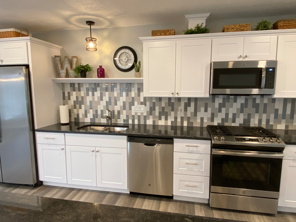 Inspiration for a large transitional l-shaped vinyl floor and gray floor open concept kitchen remodel in Cincinnati with an undermount sink, raised-panel cabinets, white cabinets, granite countertops, multicolored backsplash, ceramic backsplash, stainless steel appliances, an island and black countertops