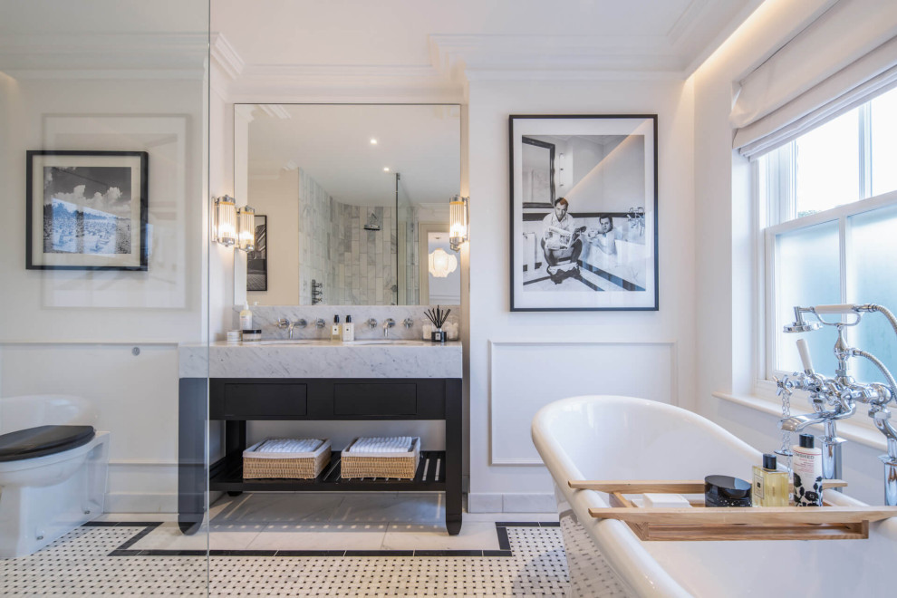 This is an example of a transitional master bathroom in London with flat-panel cabinets, black cabinets, a freestanding tub, an open shower, a one-piece toilet, marble, white walls, an undermount sink, marble benchtops, multi-coloured floor, an open shower, grey benchtops, a double vanity, a built-in vanity and panelled walls.