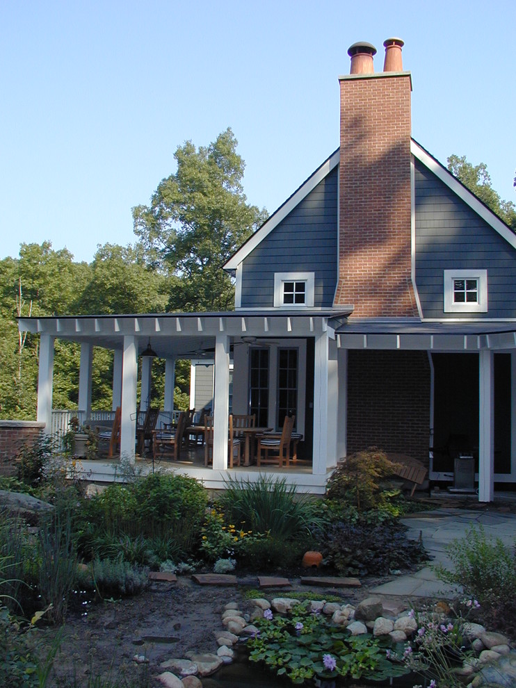 Photo of a mid-sized country backyard verandah in Detroit with a water feature, natural stone pavers and a roof extension.