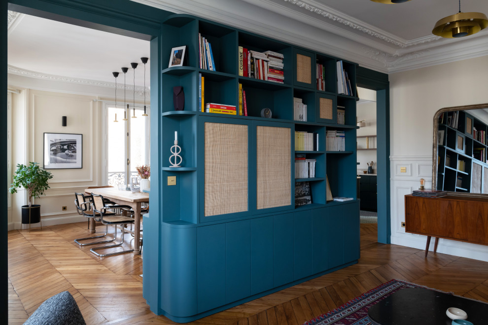 Foto di un grande soggiorno minimalista aperto con libreria, pareti blu, pavimento in legno massello medio, camino classico, cornice del camino in pietra, TV nascosta e boiserie