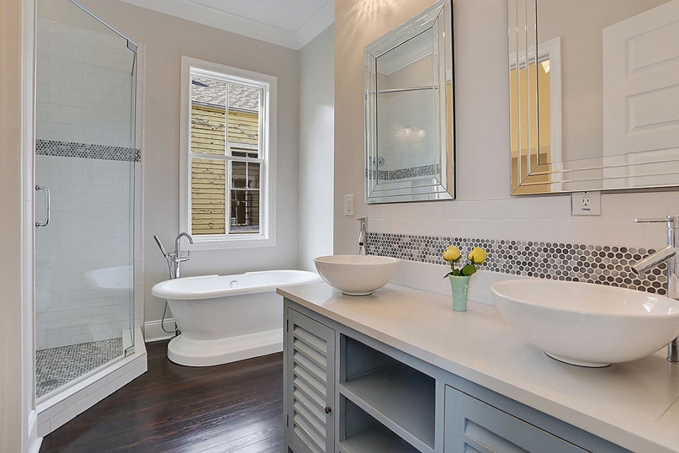 Photo of a mid-sized country master bathroom in New Orleans with furniture-like cabinets, distressed cabinets, a freestanding tub, a corner shower, multi-coloured tile, glass tile, white walls, dark hardwood floors, a vessel sink and wood benchtops.