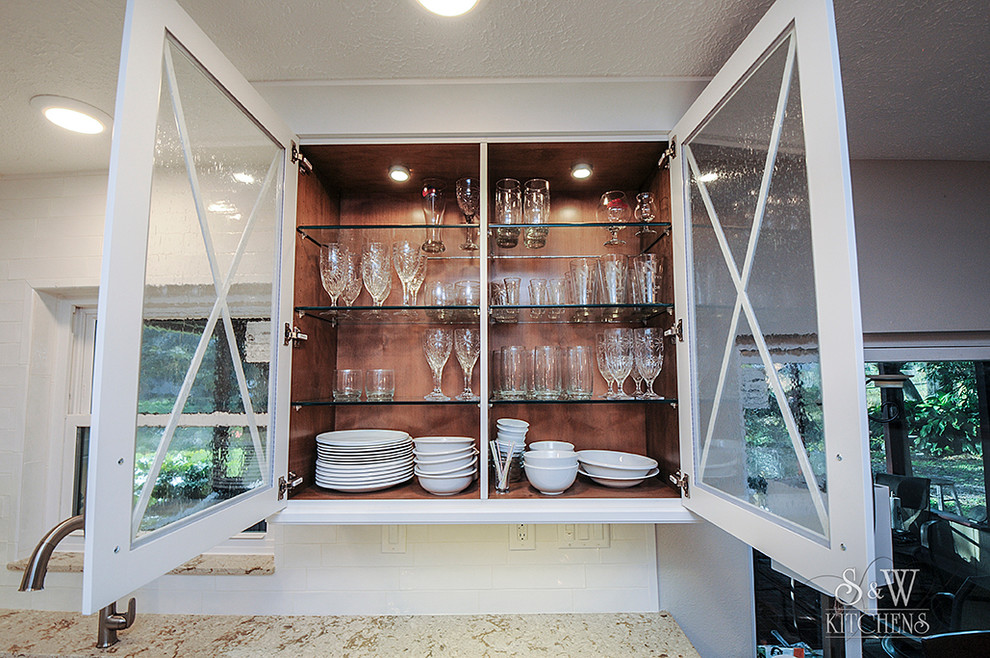 Inspiration for a mid-sized transitional galley porcelain tile eat-in kitchen remodel in Tampa with a farmhouse sink, flat-panel cabinets, white cabinets, quartz countertops, white backsplash, subway tile backsplash, stainless steel appliances and a peninsula