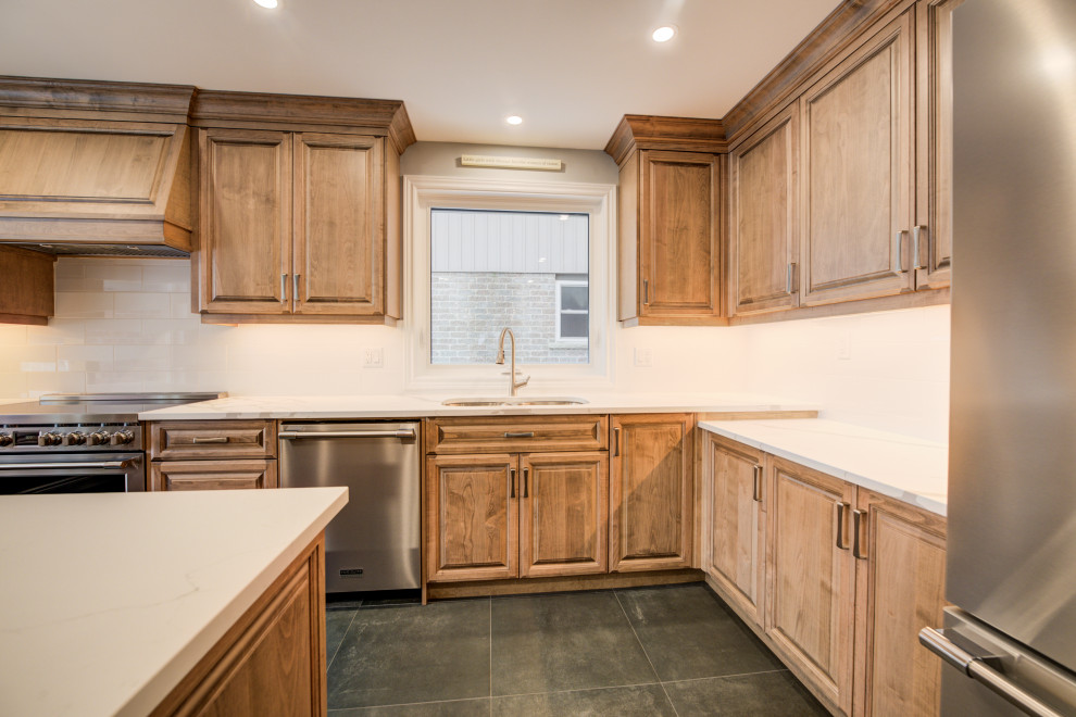 Eat-in kitchen - mid-sized transitional l-shaped eat-in kitchen idea in Toronto with an undermount sink, raised-panel cabinets, medium tone wood cabinets, quartz countertops, white backsplash, ceramic backsplash, stainless steel appliances, an island and white countertops