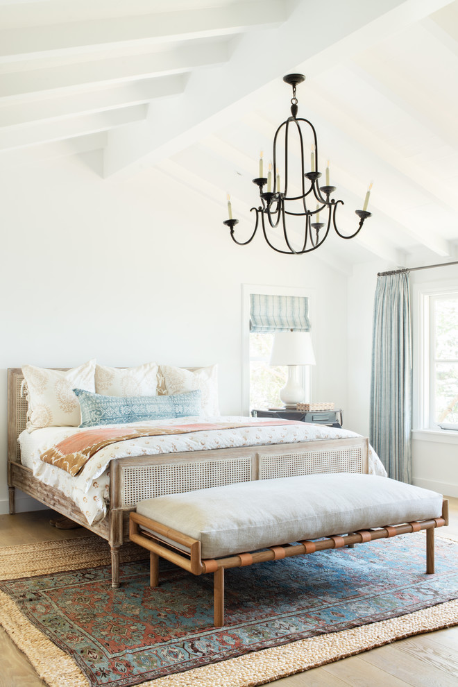 This is an example of a beach style bedroom in Los Angeles with white walls, light hardwood floors and beige floor.