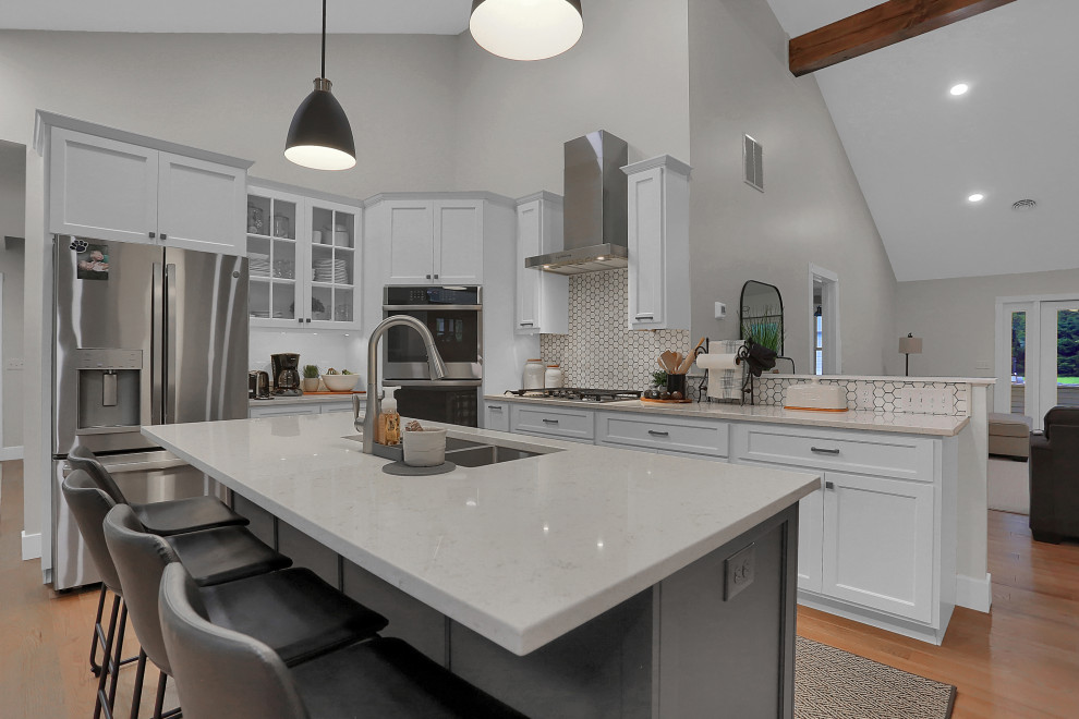 Mid-sized transitional l-shaped open concept kitchen photo with flat-panel cabinets, white cabinets, quartz countertops, gray backsplash, an island and white countertops