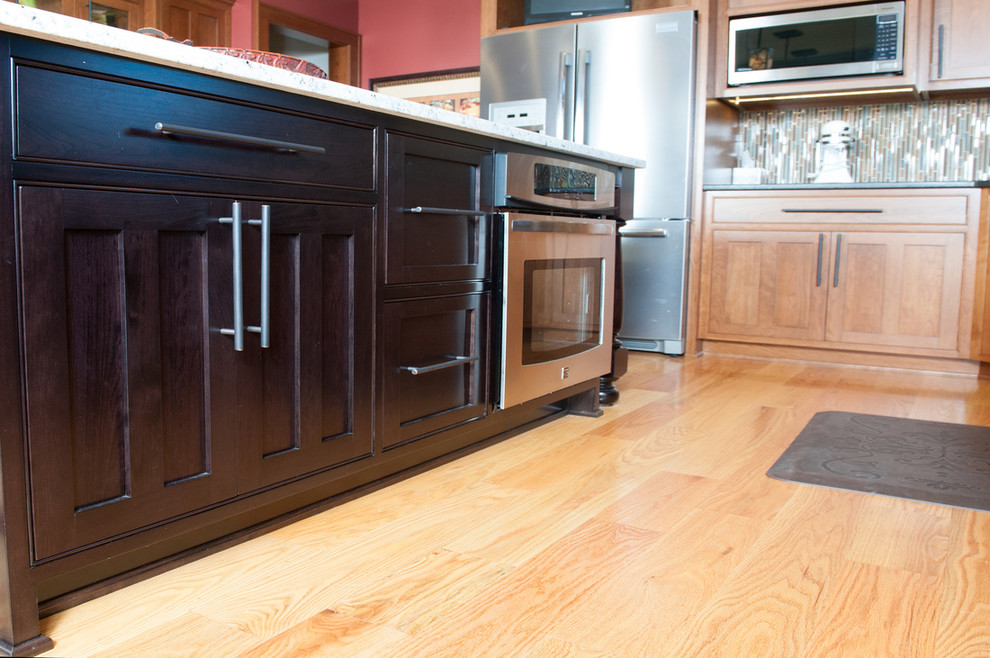 Eat-in kitchen - mid-sized transitional l-shaped medium tone wood floor eat-in kitchen idea in Orange County with a farmhouse sink, shaker cabinets, medium tone wood cabinets, granite countertops, multicolored backsplash, matchstick tile backsplash, stainless steel appliances and an island