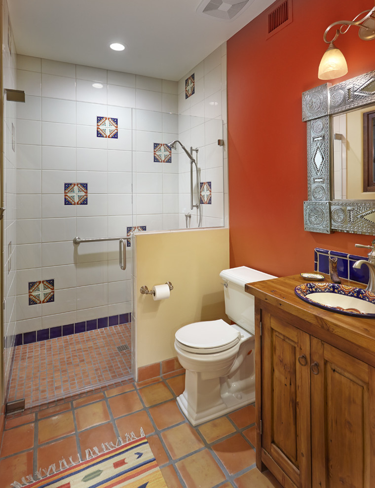 Design ideas for an expansive master bathroom in Phoenix with furniture-like cabinets, light wood cabinets, a curbless shower, a one-piece toilet, terra-cotta tile, orange walls, terra-cotta floors, a drop-in sink and wood benchtops.