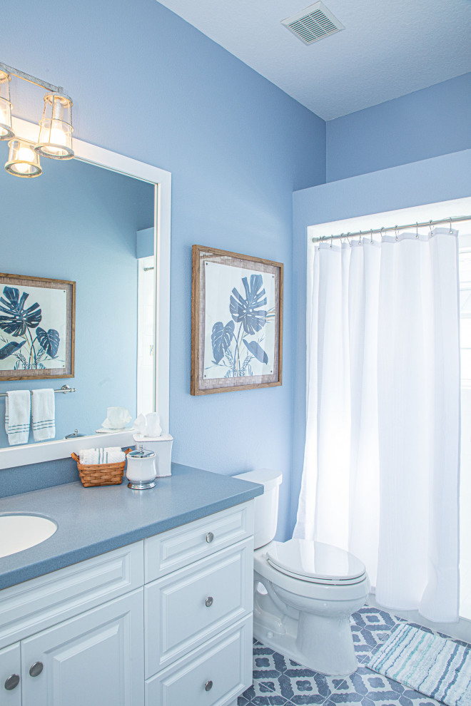 Inredning av ett modernt mellanstort blå blått en-suite badrum, med skåp i shakerstil, vita skåp, ett hörnbadkar, en dusch/badkar-kombination, en toalettstol med hel cisternkåpa, blå väggar och ett väggmonterat handfat