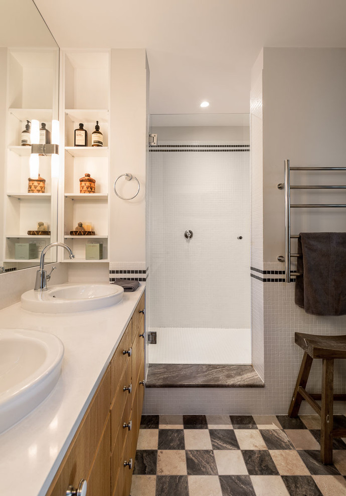 Photo of a large contemporary master wet room bathroom in Sydney with a drop-in sink, flat-panel cabinets, medium wood cabinets, white tile, mosaic tile, white walls, porcelain floors, solid surface benchtops, multi-coloured floor, an open shower and white benchtops.