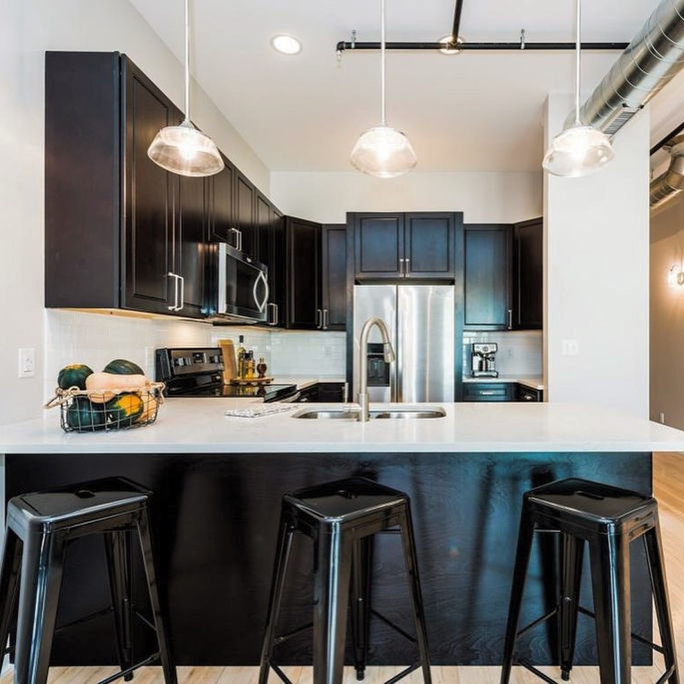 Eat-in kitchen - mid-sized transitional u-shaped eat-in kitchen idea with a double-bowl sink, shaker cabinets, white cabinets, quartz countertops, white backsplash, subway tile backsplash, stainless steel appliances, no island and white countertops