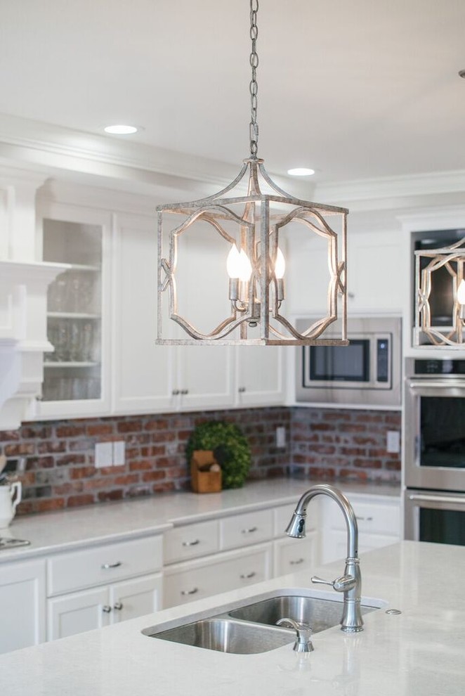 Huge l-shaped light wood floor and brown floor open concept kitchen photo with a double-bowl sink, recessed-panel cabinets, brick backsplash, stainless steel appliances and an island