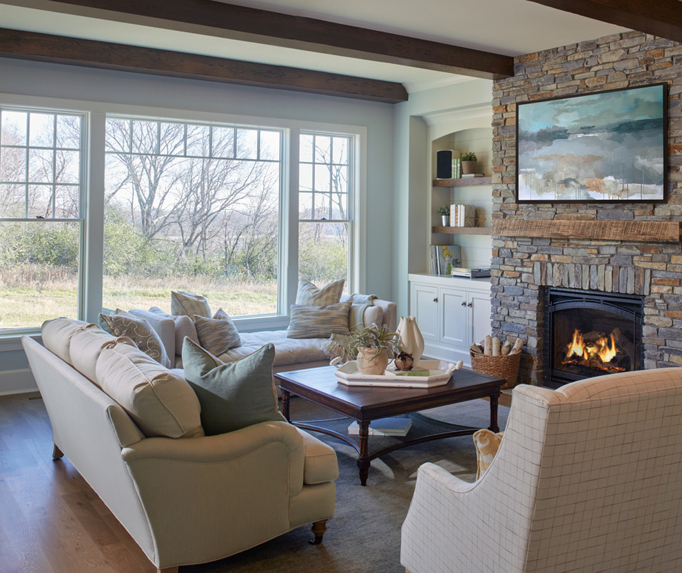 Design ideas for a mid-sized country enclosed living room in Minneapolis with beige walls, light hardwood floors, a standard fireplace, a stone fireplace surround and brown floor.