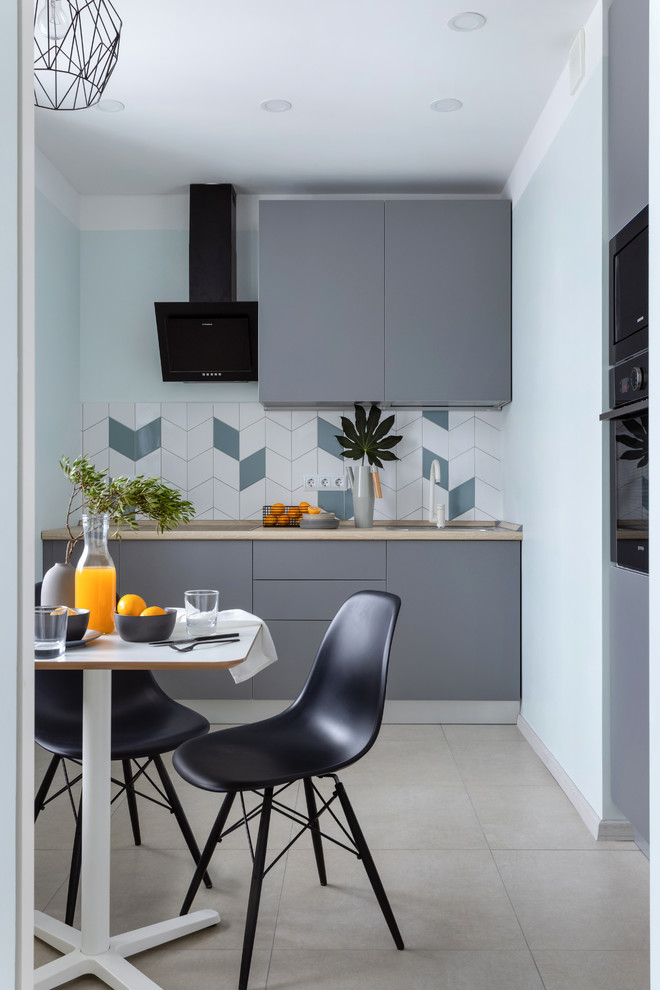 Photo of a small contemporary eat-in kitchen in Moscow with flat-panel cabinets, grey cabinets, multi-coloured splashback, black appliances, no island, beige floor and beige benchtop.