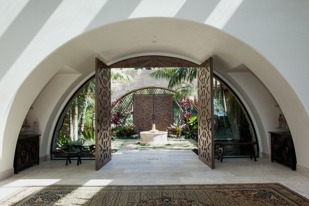 Photo of an expansive mediterranean front door in Orange County with white walls, limestone floors, a double front door and a medium wood front door.