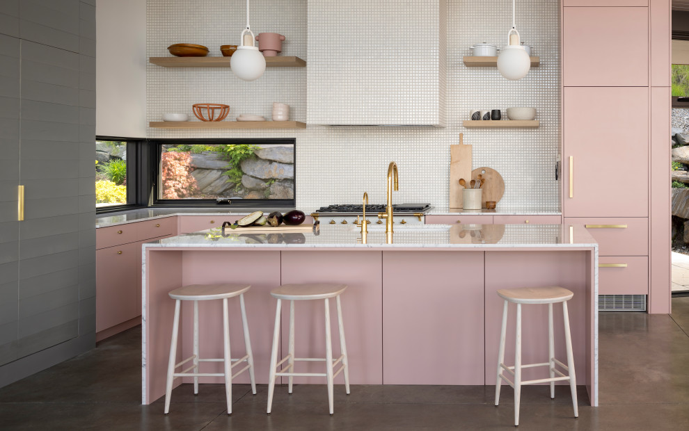 Photo of a medium sized contemporary l-shaped kitchen/diner in Other with a submerged sink, pink cabinets, marble worktops, white splashback, mosaic tiled splashback, concrete flooring, an island, flat-panel cabinets, white appliances, grey floors and multicoloured worktops.