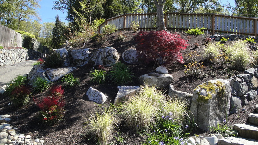 This is an example of a mid-sized transitional full sun front yard stone driveway in Seattle for summer.