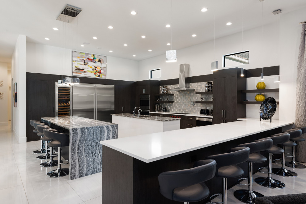 This is an example of an expansive contemporary u-shaped kitchen in Orlando with an undermount sink, flat-panel cabinets, dark wood cabinets, grey splashback, stainless steel appliances, multiple islands, white floor and white benchtop.