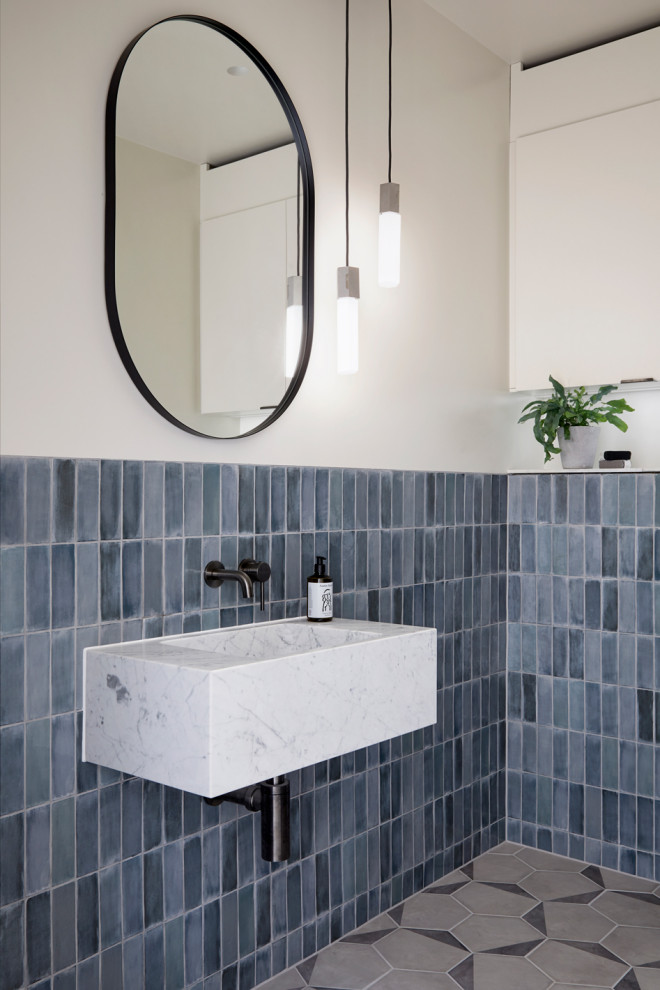 Immagine di un bagno di servizio scandinavo di medie dimensioni con piastrelle in ceramica, pareti blu, pavimento in gres porcellanato, lavabo sospeso e pavimento grigio