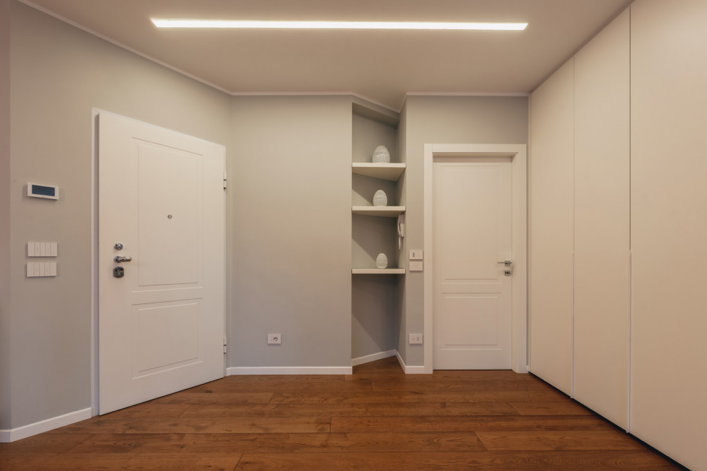 Стильный дизайн: фойе среднего размера в современном стиле с серыми стенами, деревянным полом, одностворчатой входной дверью, белой входной дверью, коричневым полом и многоуровневым потолком - последний тренд