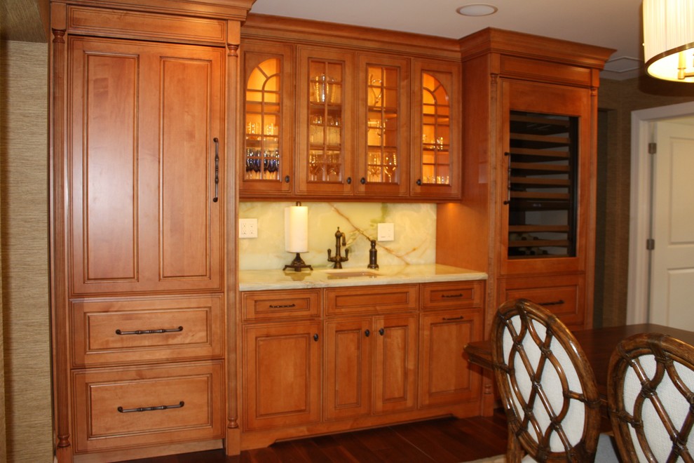 Photo of a large tropical single-wall wet bar in Miami with an undermount sink, raised-panel cabinets, medium wood cabinets, onyx benchtops, green splashback, green benchtop and dark hardwood floors.