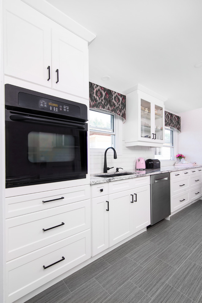Example of a mid-sized transitional galley porcelain tile and gray floor eat-in kitchen design with a double-bowl sink, shaker cabinets, white cabinets, granite countertops, white backsplash, subway tile backsplash, stainless steel appliances, no island and gray countertops