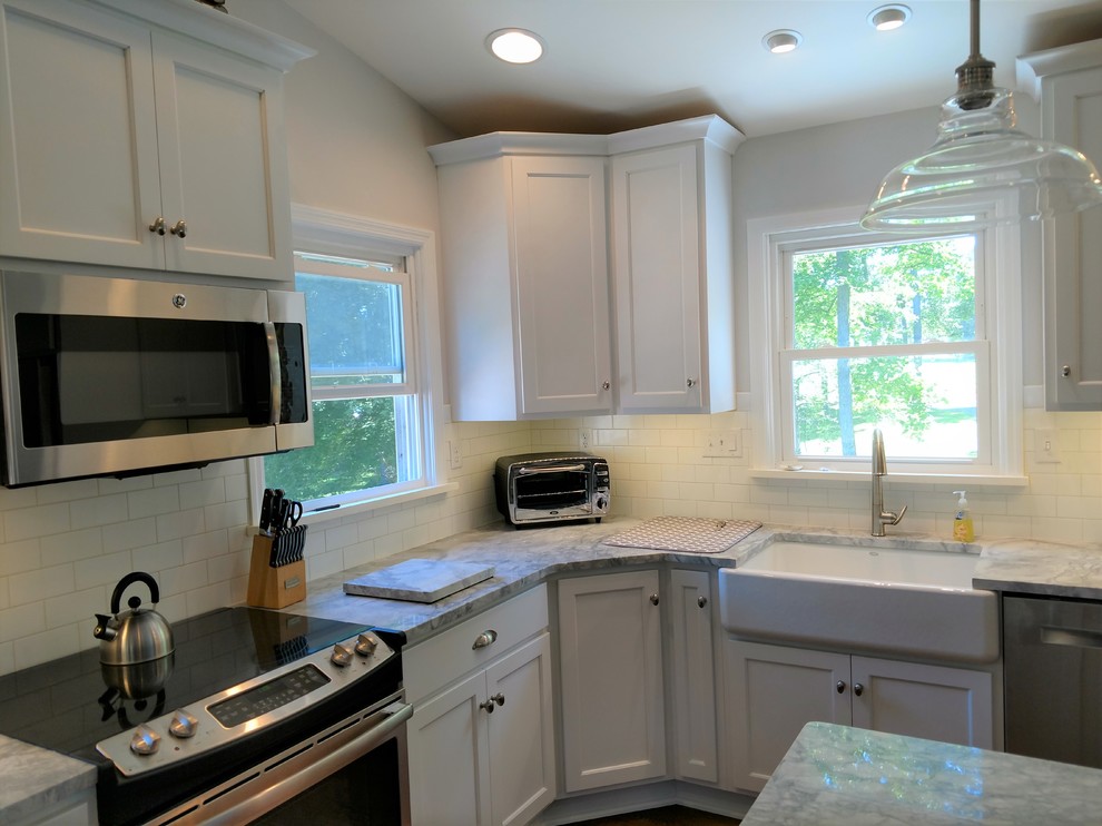 Kitchen - large transitional l-shaped medium tone wood floor and brown floor kitchen idea with a farmhouse sink, flat-panel cabinets, white cabinets, white backsplash, subway tile backsplash, stainless steel appliances, an island and multicolored countertops