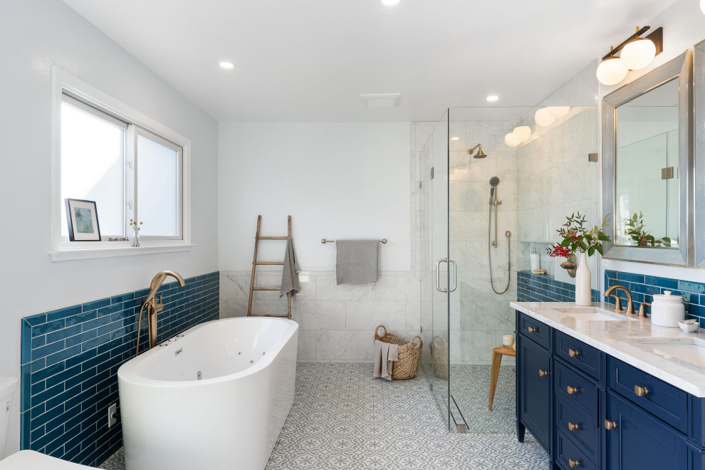 Пример оригинального дизайна: главная ванная комната среднего размера в стиле неоклассика (современная классика) с синими фасадами, накладной ванной, угловым душем, биде, синей плиткой, керамической плиткой, белыми стенами, полом из мозаичной плитки, врезной раковиной, мраморной столешницей, серым полом, душем с распашными дверями, белой столешницей, тумбой под две раковины, встроенной тумбой, кессонным потолком и фасадами с утопленной филенкой