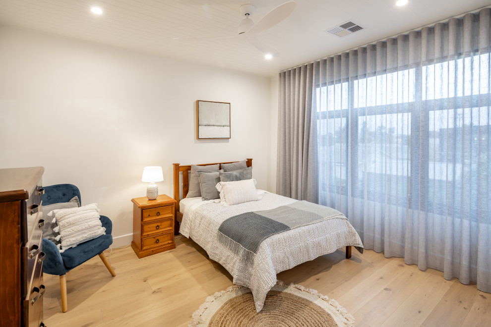 Photo of a mid-sized guest bedroom in Adelaide with white walls, light hardwood floors and brown floor.