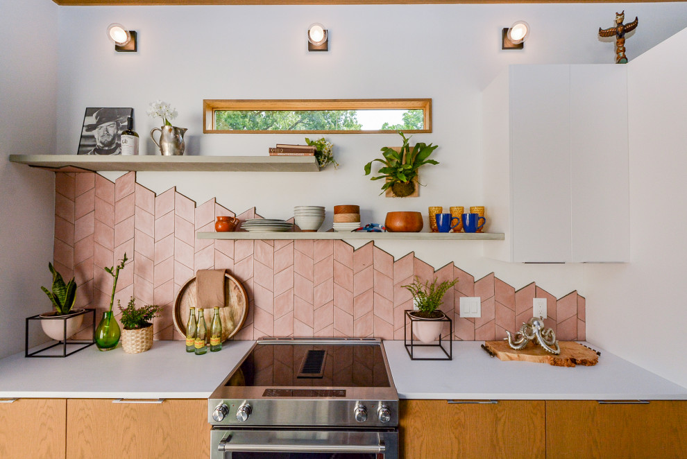 This is an example of a mid-sized eclectic galley eat-in kitchen in Houston with an undermount sink, flat-panel cabinets, light wood cabinets, concrete benchtops, pink splashback, terra-cotta splashback, stainless steel appliances, concrete floors, with island, grey floor, white benchtop and exposed beam.