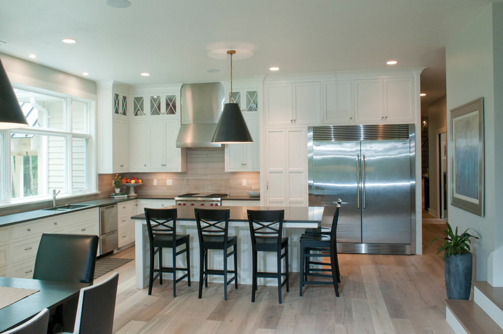 Mid-sized transitional l-shaped light wood floor and beige floor eat-in kitchen photo with an undermount sink, shaker cabinets, white cabinets, solid surface countertops, multicolored backsplash, porcelain backsplash, stainless steel appliances and an island