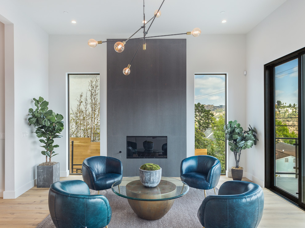 This is an example of a mid-sized midcentury open concept living room in Los Angeles with a standard fireplace, a tile fireplace surround, no tv, white walls, light hardwood floors and brown floor.